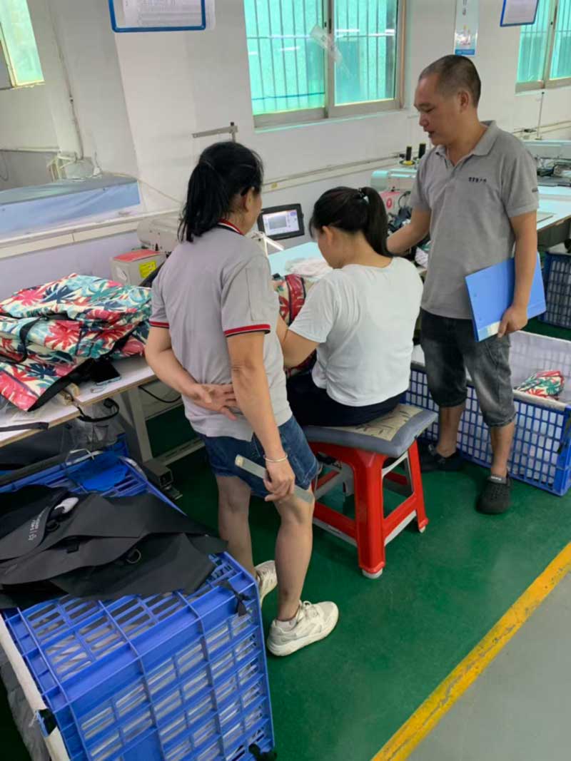 Supervisor reviewing a part with two sewing operators at the machine
